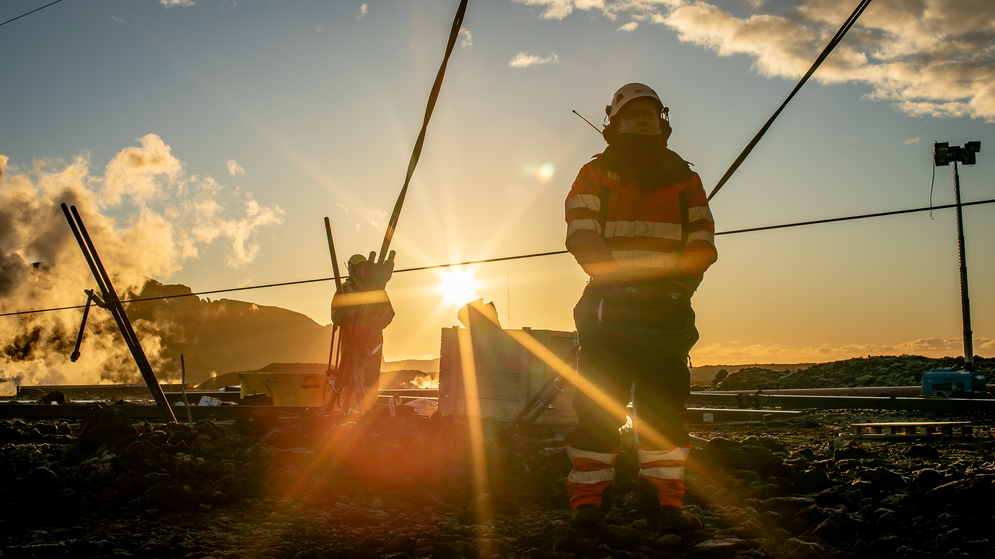 Vinna við viðhald á háspennulínum við sólsetur